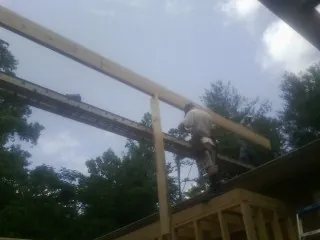 Carpenter setting a ridge beam over a new addition frame — Ice Dam Removal by Roofing Brothers in Spicewood