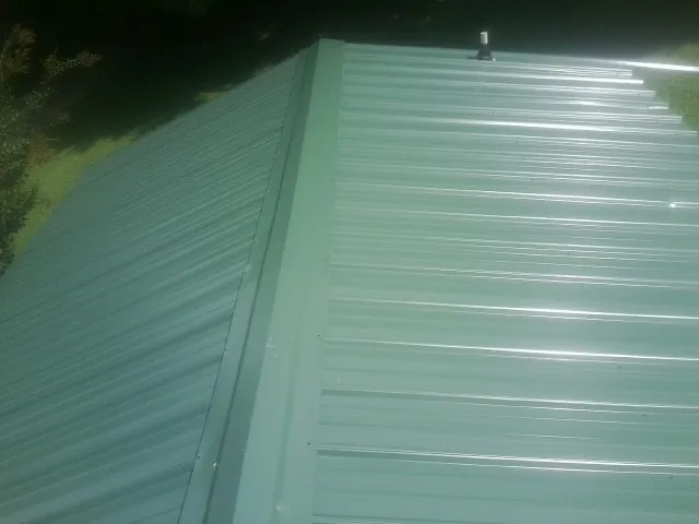New green metal panels meeting at the ridge of a roof — Flat Roof Repair work by our crew in Spicewood