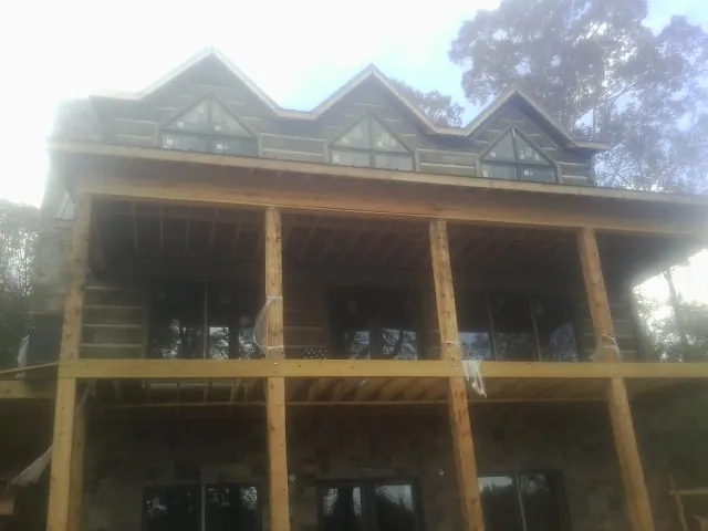 Dormers and porch framing on a large log home under construction — Roof Coating work by our crew in Spicewood