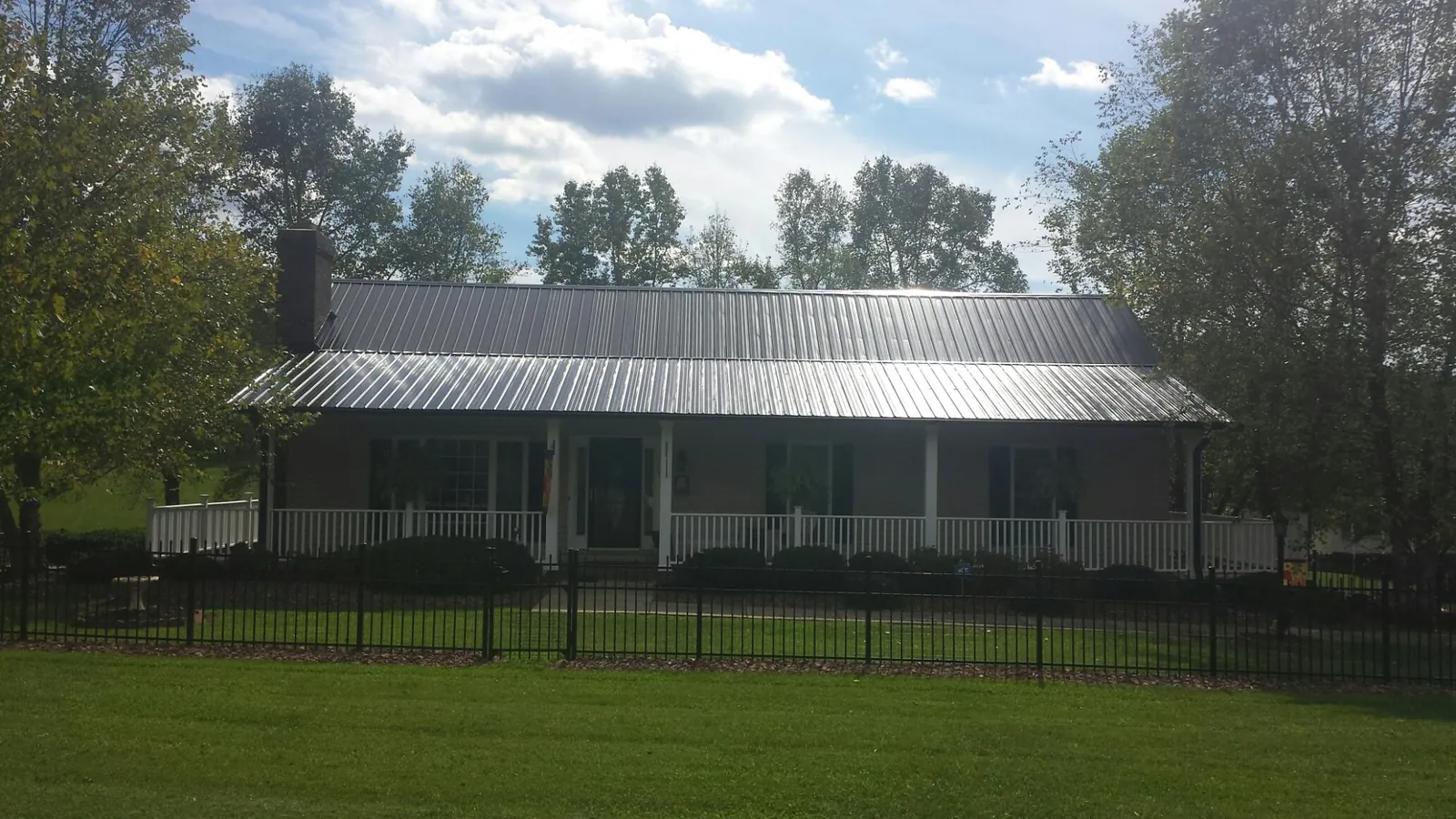 Gray metal roof on a brick ranch with a full width front porch — Gutter Guard Installation work by our crew in Spicewood