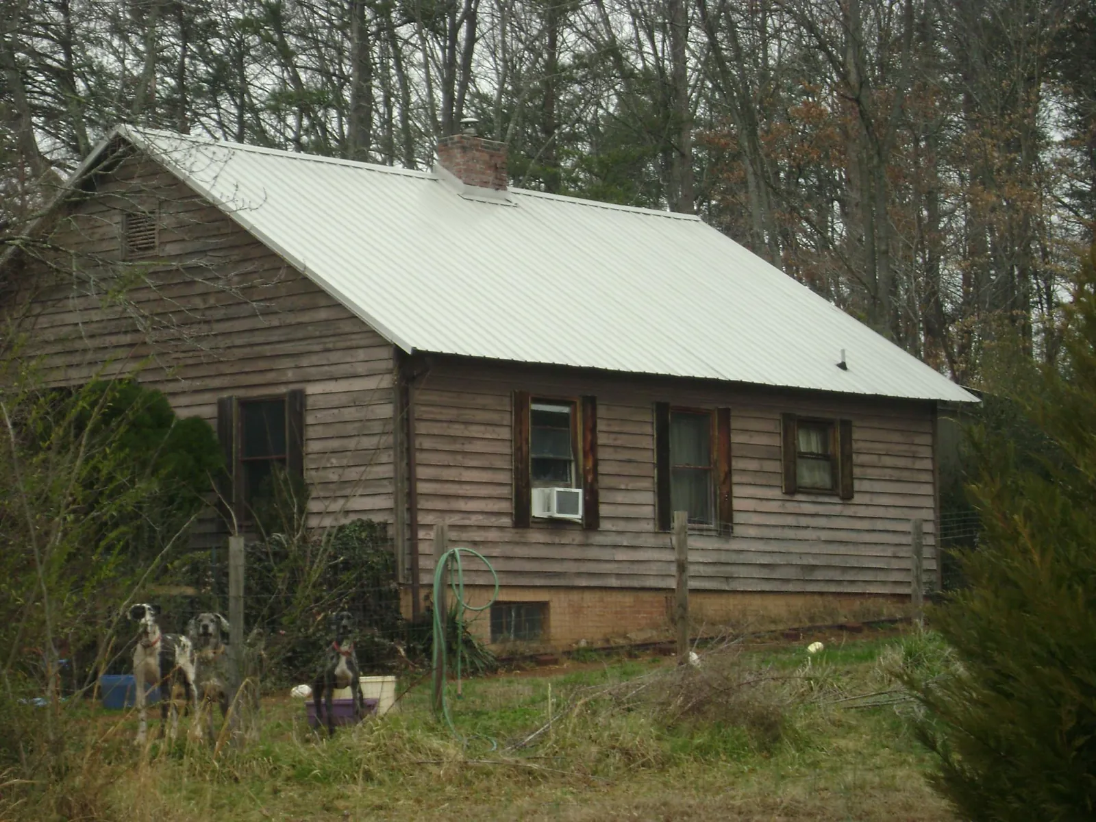 White metal roof on an old wood sided farmhouse, from a Metal Roof Installation job in Spicewood