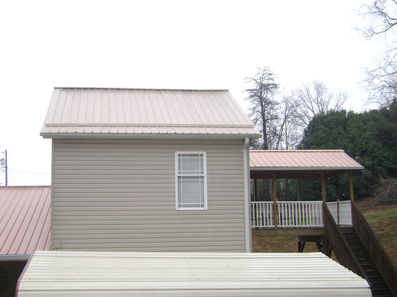 Tan metal roofs on a two story addition and attached porch, from a Roof Replacement job in Spicewood