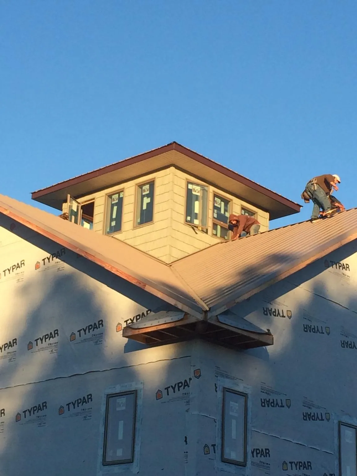 Roofers working around a rooftop cupola on a new metal roof at sunset — Roof Waterproofing in Spicewood by Roofing Brothers